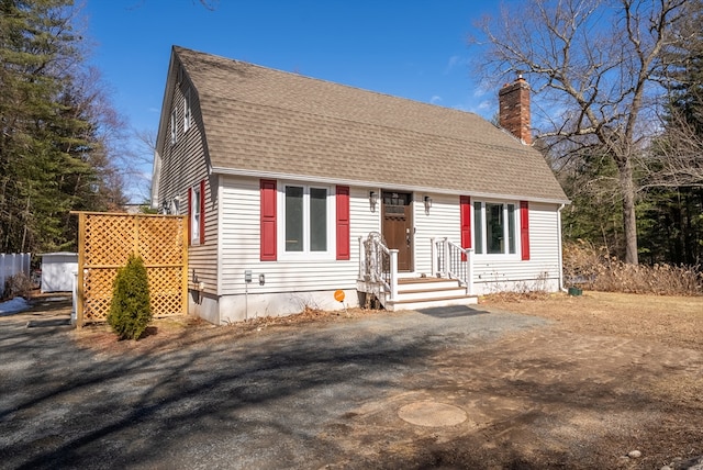 view of front of home with a shingled roof and a chimney