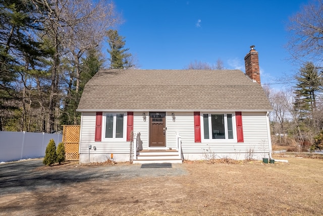 view of front of house featuring fence, roof with shingles, and a chimney