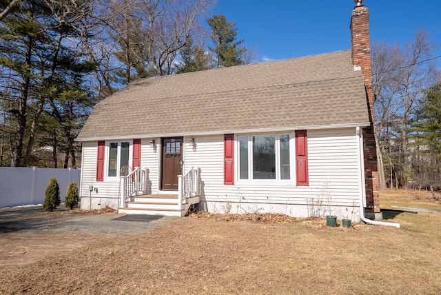 colonial inspired home with a chimney, fence, and a shingled roof