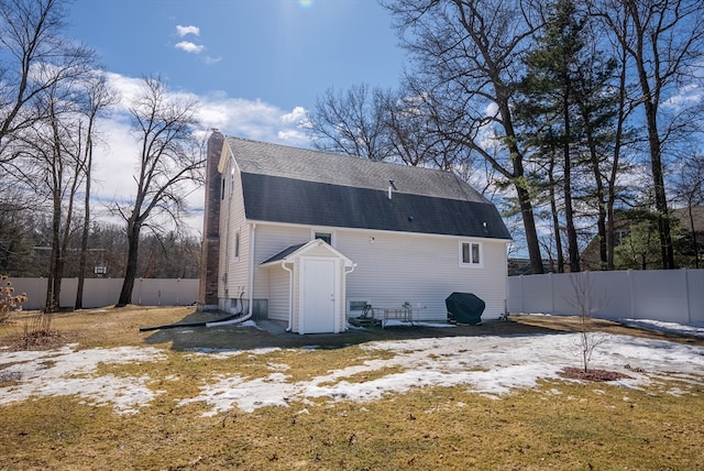 back of house with a gambrel roof, a shingled roof, and a fenced backyard