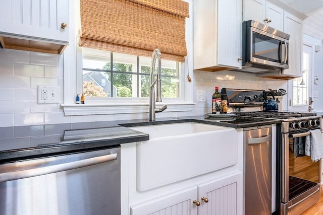 kitchen with appliances with stainless steel finishes, decorative backsplash, white cabinets, wood-type flooring, and sink