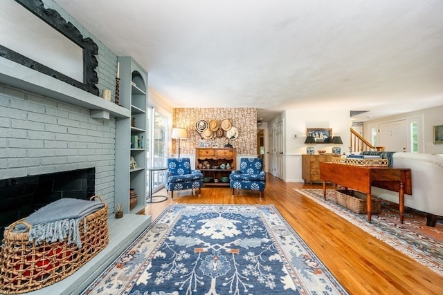 living room featuring brick wall, a fireplace, and hardwood / wood-style floors