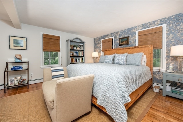 bedroom with wood-type flooring and a baseboard heating unit