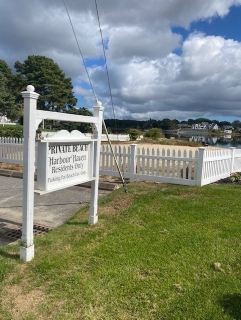 community sign with a yard and a water view