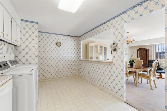 washroom featuring a notable chandelier, cabinet space, washing machine and clothes dryer, and wallpapered walls