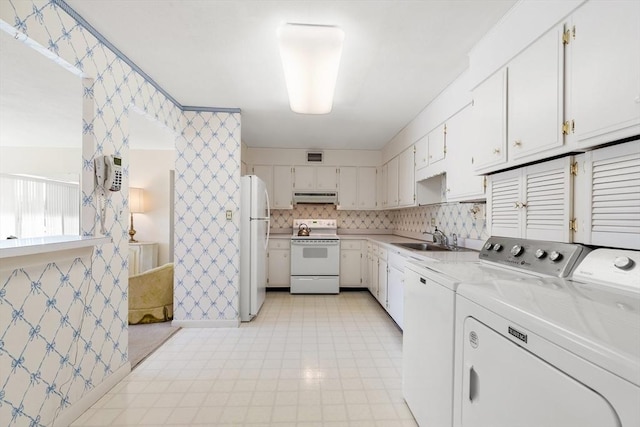 clothes washing area with visible vents, wallpapered walls, washing machine and dryer, laundry area, and a sink