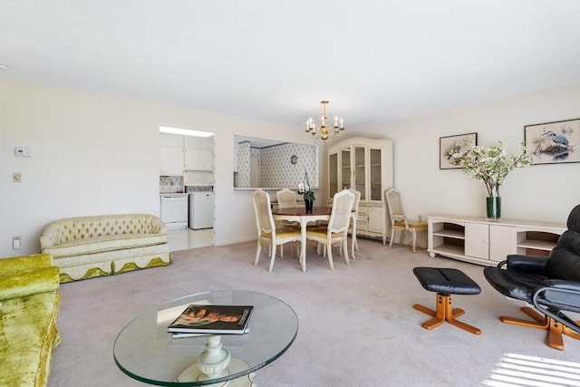 living area featuring light carpet, a notable chandelier, and washer and clothes dryer