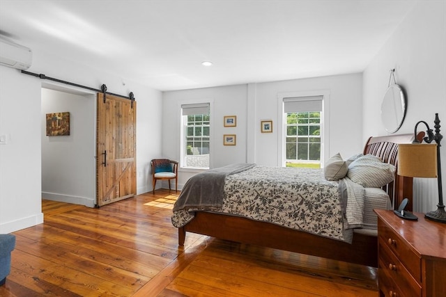 166 Littleton Unit 3, Harvard, MA 01451 - bedroom with a barn door, hardwood / wood-style floors, an AC wall unit, and recessed lighting