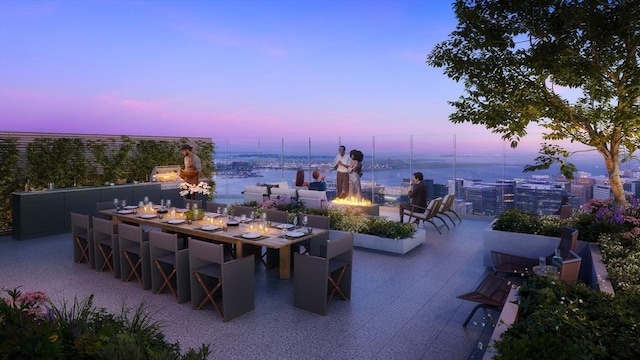 patio terrace at dusk featuring a bar and an outdoor fire pit