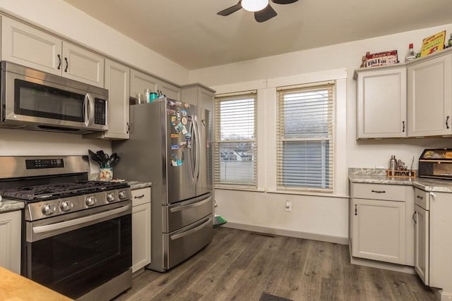 kitchen featuring light stone countertops, appliances with stainless steel finishes, dark hardwood / wood-style flooring, and ceiling fan