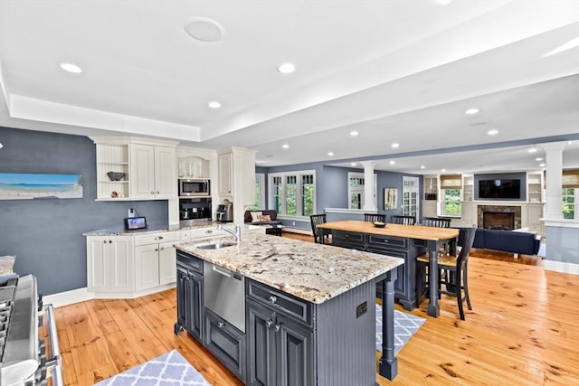 148 Pond St, Cohasset, MA 02025 - kitchen featuring appliances with stainless steel finishes, a sink, light wood-style flooring, white cabinets, and recessed lighting