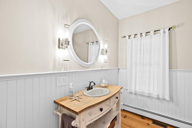 148 Pond St, Cohasset, MA 02025 - bathroom featuring a baseboard heating unit, a wainscoted wall, vanity, and wood finished floors