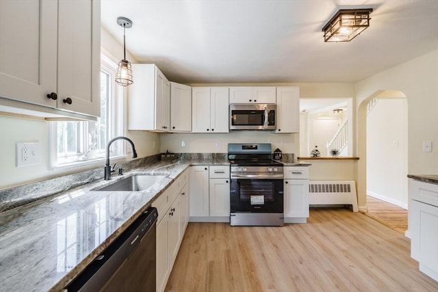 76 Wolcott Ave, West Springfield, MA 01089 - kitchen with radiator, stainless steel appliances, a sink, light stone countertops, and light wood-style floors