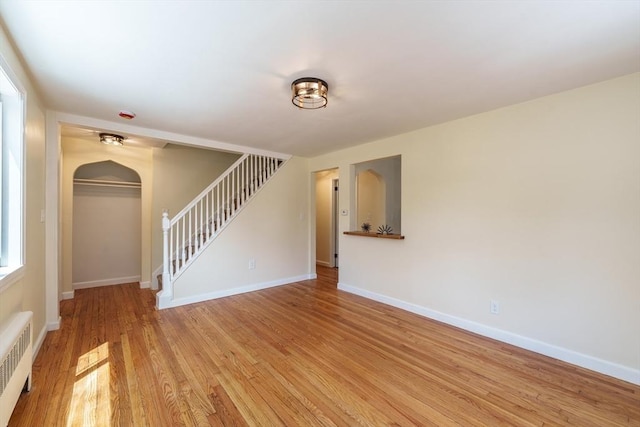 76 Wolcott Ave, West Springfield, MA 01089 - spare room featuring radiator, arched walkways, stairs, light wood-style floors, and baseboards