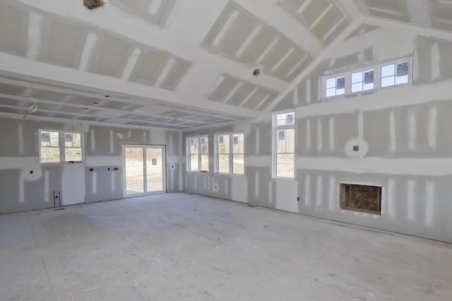 unfurnished living room with high vaulted ceiling and a healthy amount of sunlight