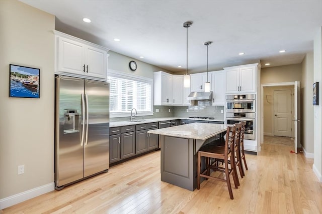 kitchen featuring gray cabinetry, a sink, under cabinet range hood, white cabinetry, and appliances with stainless steel finishes