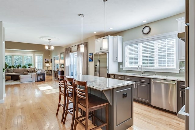 kitchen featuring a breakfast bar area, light wood-style flooring, a sink, stainless steel appliances, and open floor plan