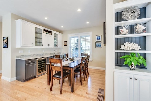 dining area featuring beverage cooler, recessed lighting, light wood finished floors, and baseboards