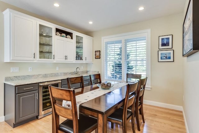 dining room with recessed lighting, light wood-style flooring, wine cooler, and wet bar