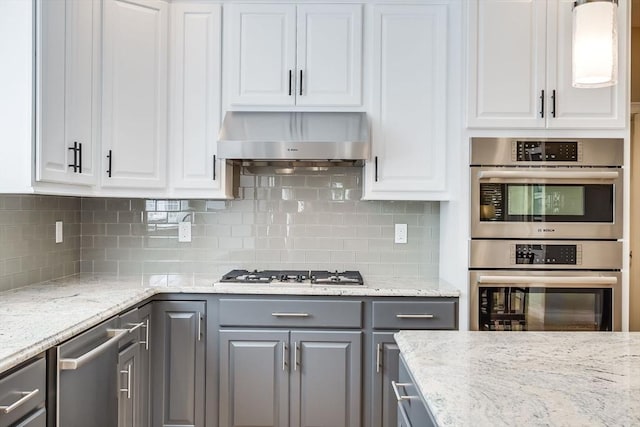 kitchen with wall chimney range hood, white cabinets, appliances with stainless steel finishes, and gray cabinetry