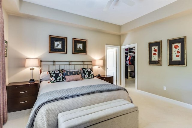 carpeted bedroom featuring a spacious closet, ceiling fan, a closet, and baseboards