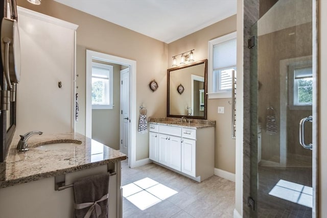 bathroom featuring a shower stall, two vanities, a healthy amount of sunlight, and a sink