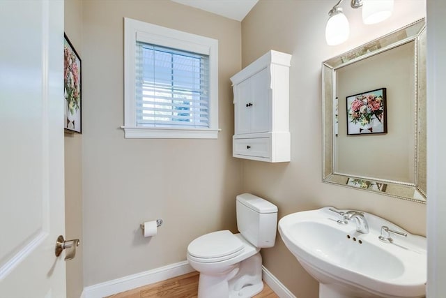 bathroom featuring a sink, baseboards, toilet, and wood finished floors