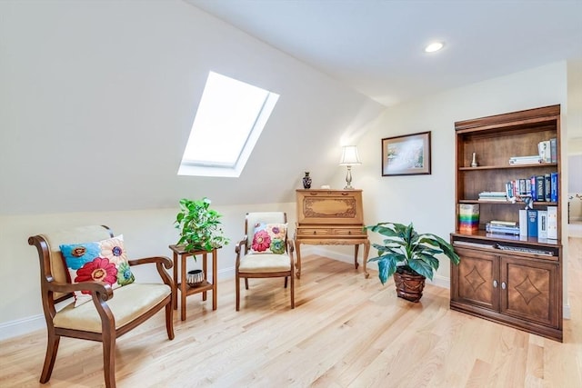 living area featuring light wood finished floors, recessed lighting, lofted ceiling with skylight, and baseboards