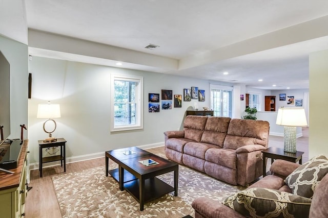 living room featuring visible vents, a healthy amount of sunlight, baseboards, and wood finished floors