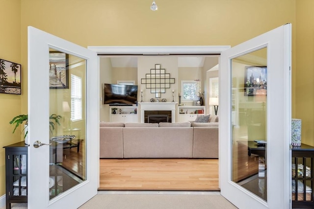 living area featuring wood finished floors, a fireplace, and french doors