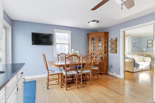 dining room featuring light wood-type flooring, a baseboard radiator, baseboards, and a ceiling fan