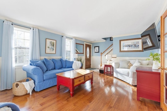 living area featuring stairs, a wainscoted wall, wood finished floors, and a wealth of natural light