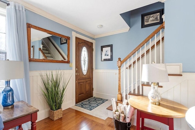 entryway featuring stairs, ornamental molding, wainscoting, and wood finished floors