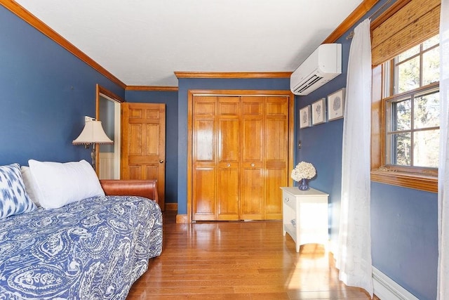 bedroom with crown molding, baseboards, wood finished floors, and a wall mounted air conditioner