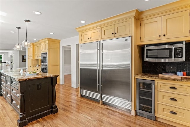 11 Ashford Ln, Andover, MA 01810 - kitchen featuring appliances with stainless steel finishes, beverage cooler, cream cabinets, light stone counters, and light wood-style flooring