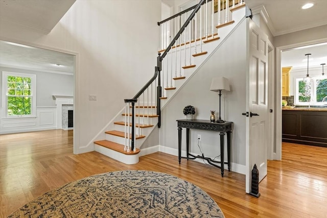 11 Ashford Ln, Andover, MA 01810 - staircase featuring wood finished floors, crown molding, plenty of natural light, a fireplace with flush hearth, and recessed lighting