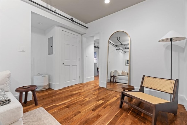 living area with wood finished floors, electric panel, and recessed lighting
