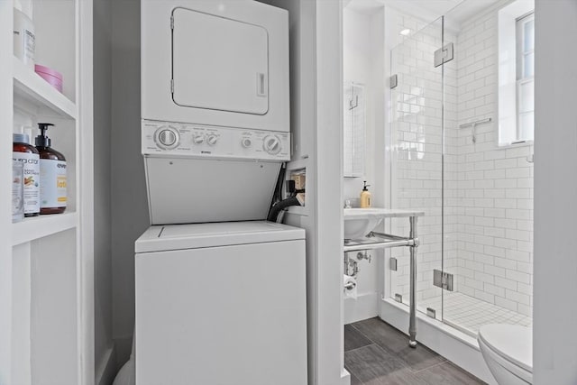 washroom with stacked washer / drying machine and dark wood-style floors