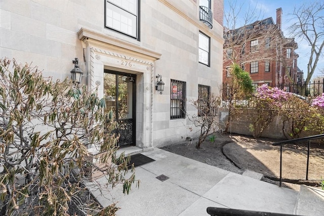 doorway to property featuring stone siding and fence