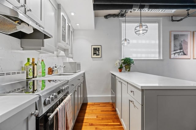 kitchen with stainless steel electric range oven, under cabinet range hood, a sink, light countertops, and light wood-style floors
