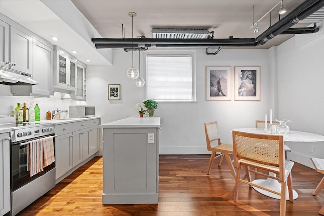 kitchen with stainless steel electric range, under cabinet range hood, wood finished floors, light countertops, and glass insert cabinets