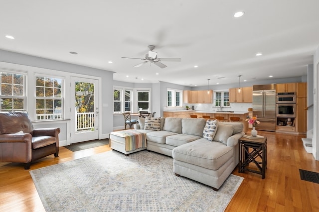 living room featuring sink, ceiling fan, a wealth of natural light, and light wood-type flooring