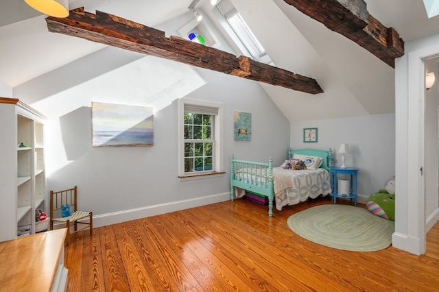 bedroom featuring lofted ceiling with skylight and hardwood / wood-style flooring