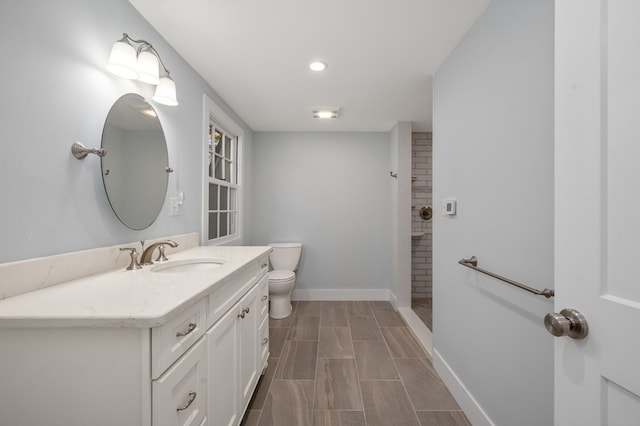 bathroom with vanity, toilet, and a tile shower