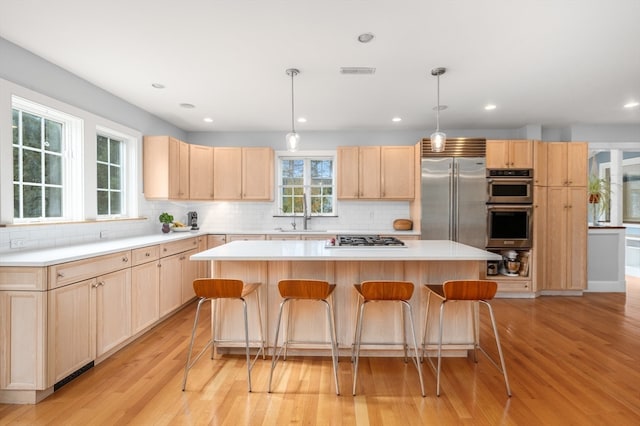 kitchen with stainless steel appliances, light wood-type flooring, and a kitchen island