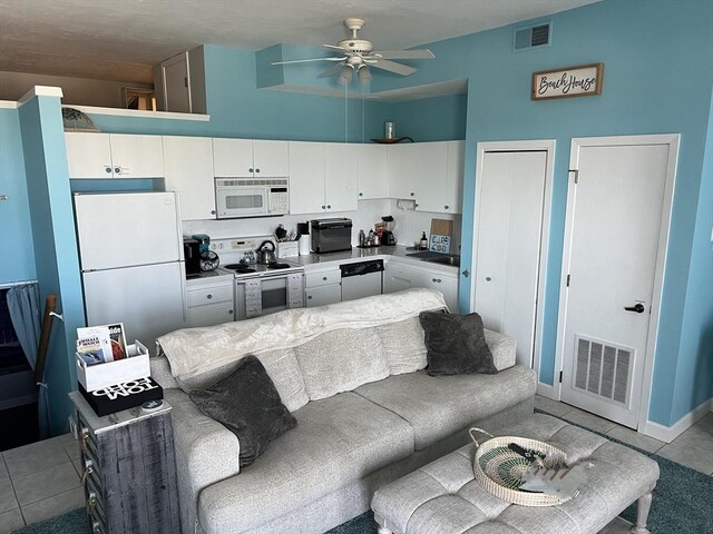 kitchen with white cabinetry, light tile patterned floors, white appliances, and ceiling fan