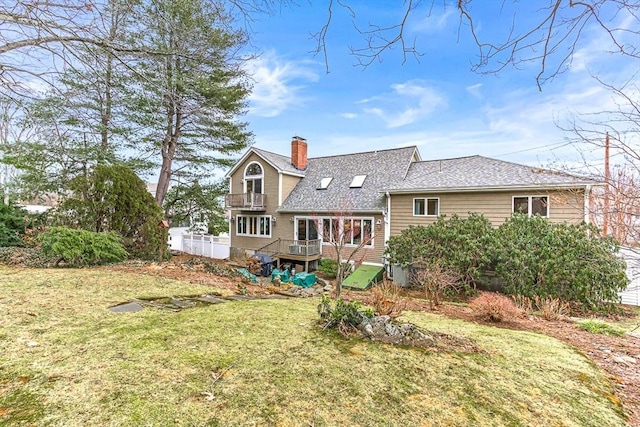 rear view of property with a balcony and a lawn