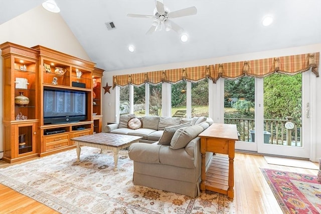 living room featuring lofted ceiling, light hardwood / wood-style flooring, and a healthy amount of sunlight