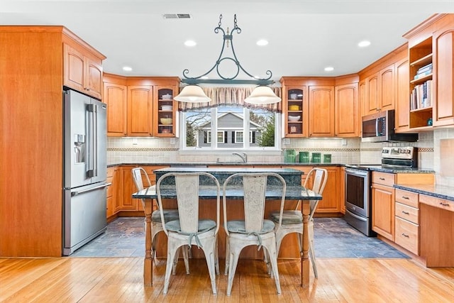 kitchen featuring stainless steel appliances, hanging light fixtures, a center island, and a kitchen bar