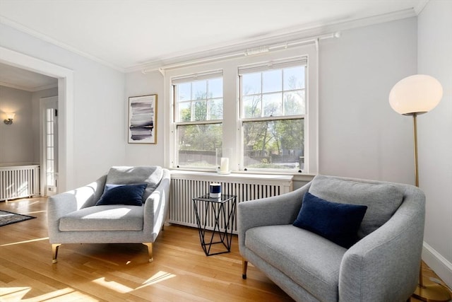 sitting room with crown molding, radiator heating unit, and wood finished floors